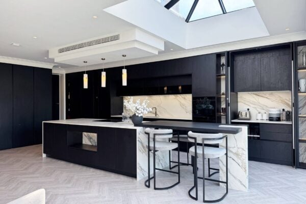 Dark kitchen island with statement stone worktop and warm pendant lighting