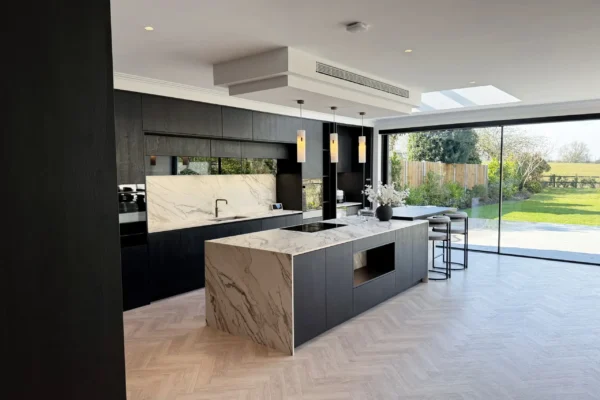 Open-plan dark kitchen with statement stone surfaces and natural wood flooring